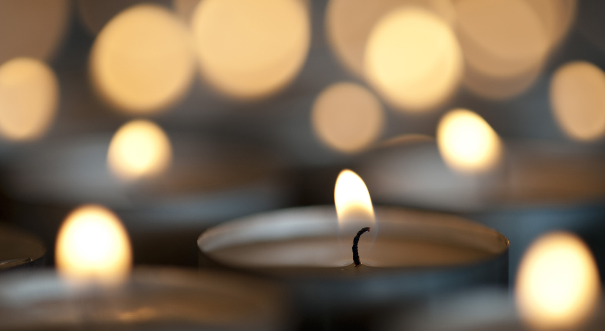Christmas candle bokeh with multiple flames but focus to the buring wick of only one candle with copyspace